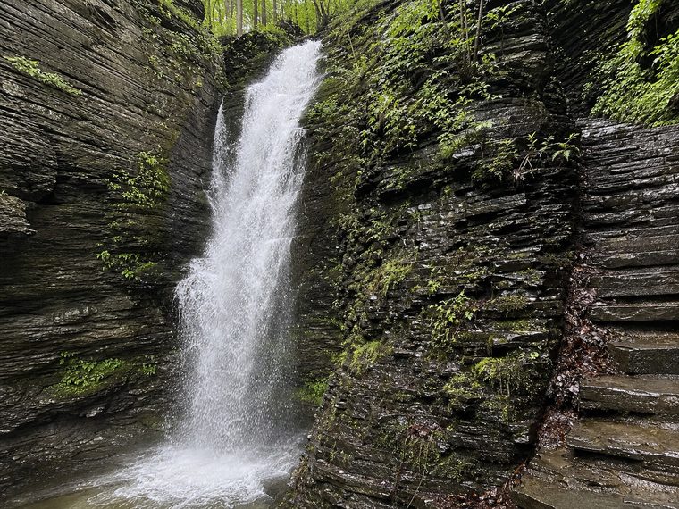 A waterfall over stone steps on a gorge trail